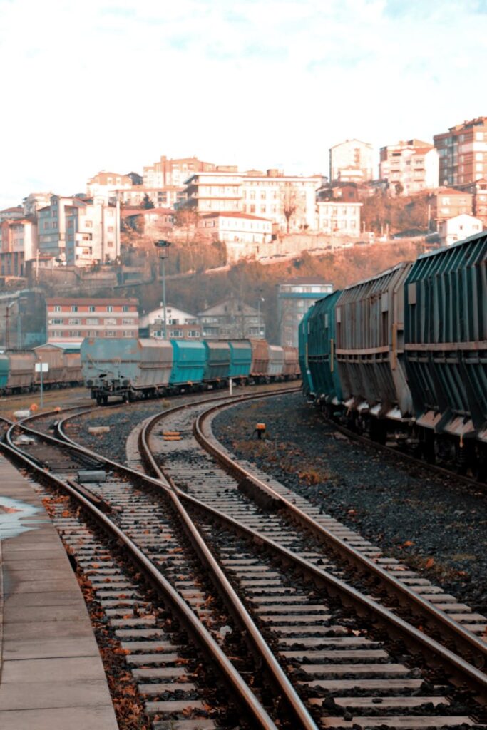 Freight trains on winding tracks near a hillside town on a clear day.